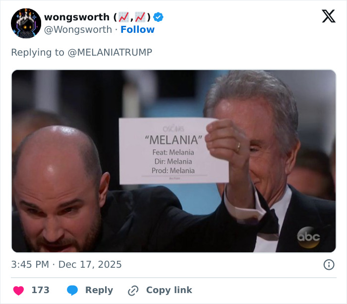 Two men in tuxedos holding up a card humorously listing Melania as director, producer, and feature of a documentary. Two men in tuxedos holding up a card humorously listing Melania as director, producer, and feature of a documentary.