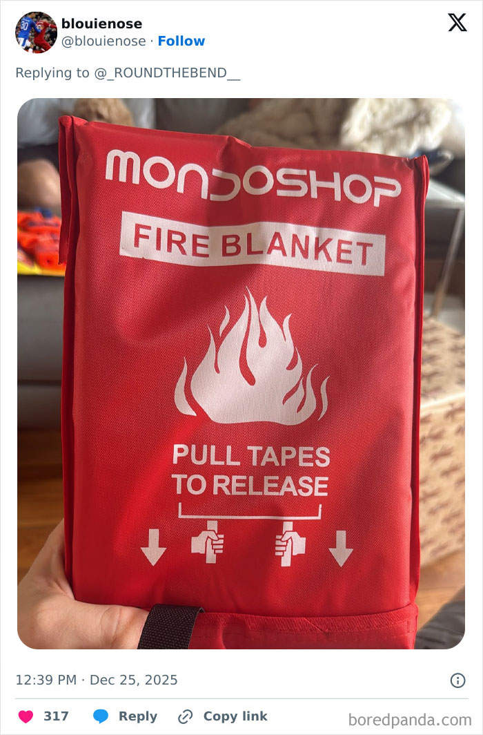 Red fire blanket packaging with instructions being held, illustrating one of the worst Xmas presents people received this holiday.