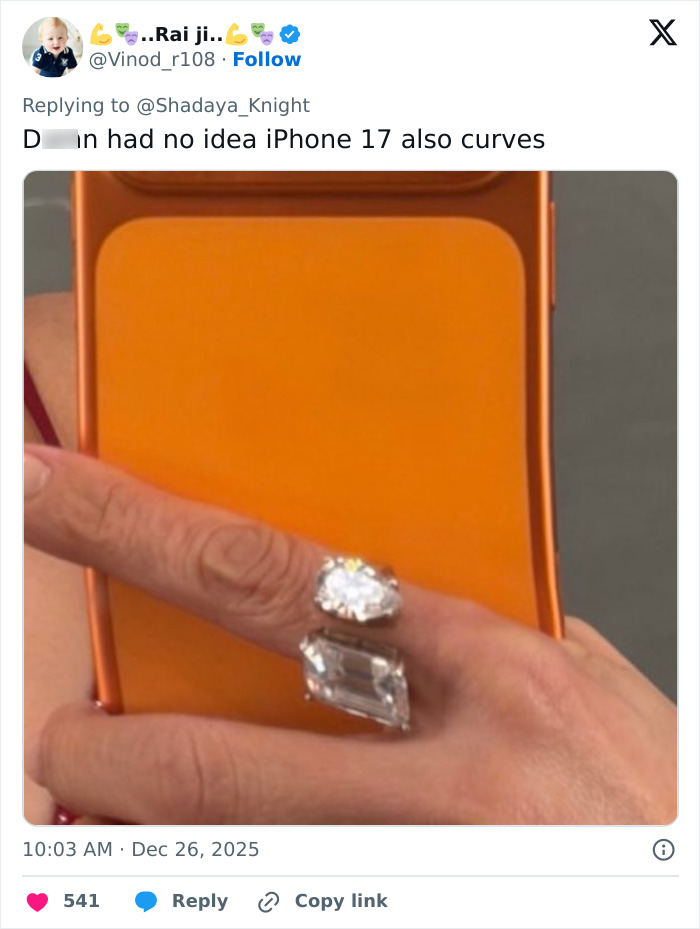 Close-up of hand holding orange phone with two large rings, highlighting odd detail prompting Photoshop skills discussion.