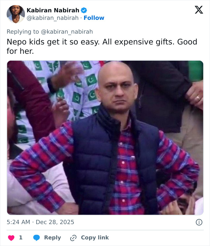 Man in a plaid shirt and vest at an event, expressing displeasure, related to backlash over intimate gift to daughter