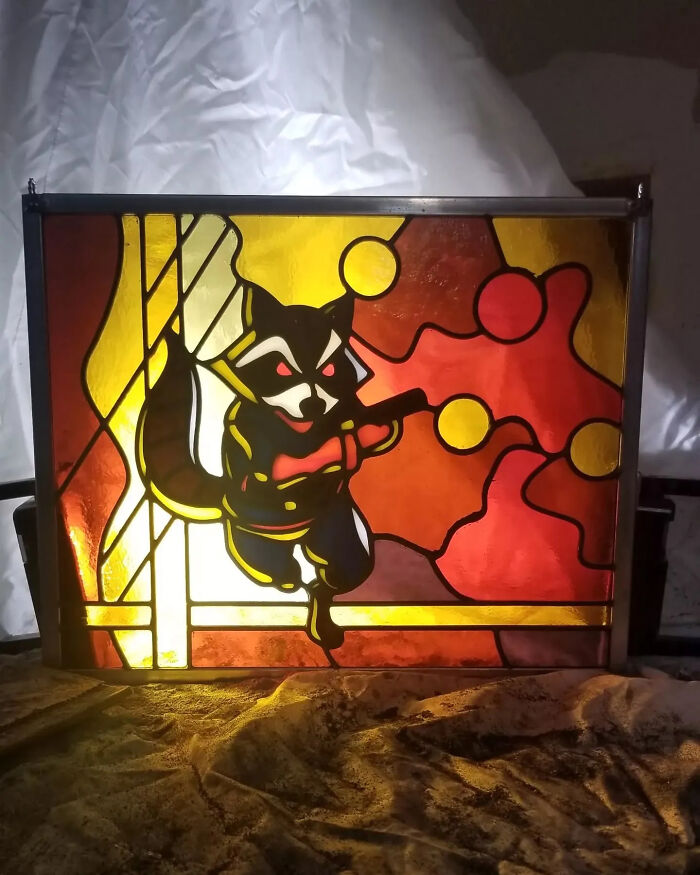 Vivid stained glass sign featuring a pop culture icon raccoon character in bright orange and yellow hues.