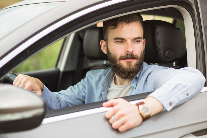 Man with beard sitting in a car looking outside, symbolizing men missed delivery of babies and important moments.