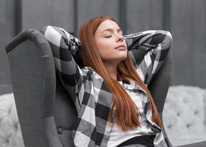 Young woman relaxing with eyes closed in armchair, illustrating small tricks for easier grown-up life.