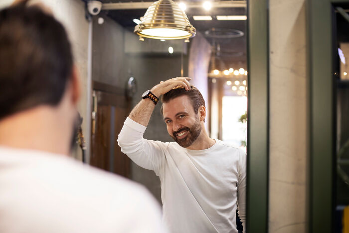 Man smiling at himself in the mirror, capturing embarrassing moments people thought no one was looking.