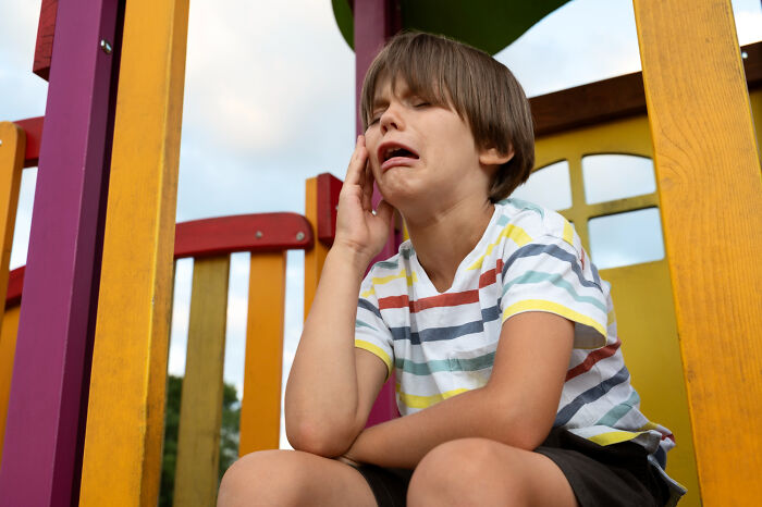 Young boy on colorful playground showing a sneaky act of revenge with a playful and dramatic expression