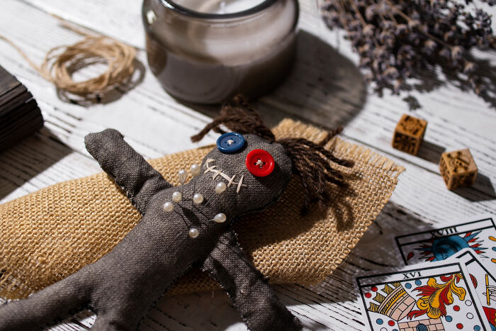 Voodoo doll with pins, tarot cards, and mystical items representing crazy things people do believing their ex will pine for them.