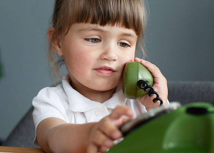 Young girl holding a green phone receiver dialing, illustrating 911 operators handling non-emergency calls.