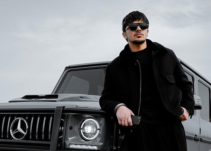 Man wearing sunglasses leaning on a luxury car, illustrating insights from people in luxury industries about rip-offs.