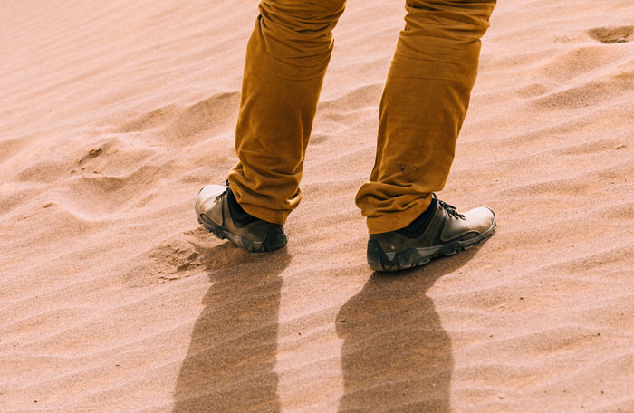 Person wearing brown pants and hiking shoes standing on sandy ground, relating to people in the woods who couldn't sleep.