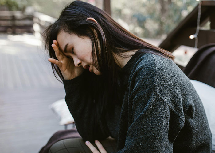 Young woman sitting outdoors looking distressed and overwhelmed, reflecting on wild stories about their ex behavior.