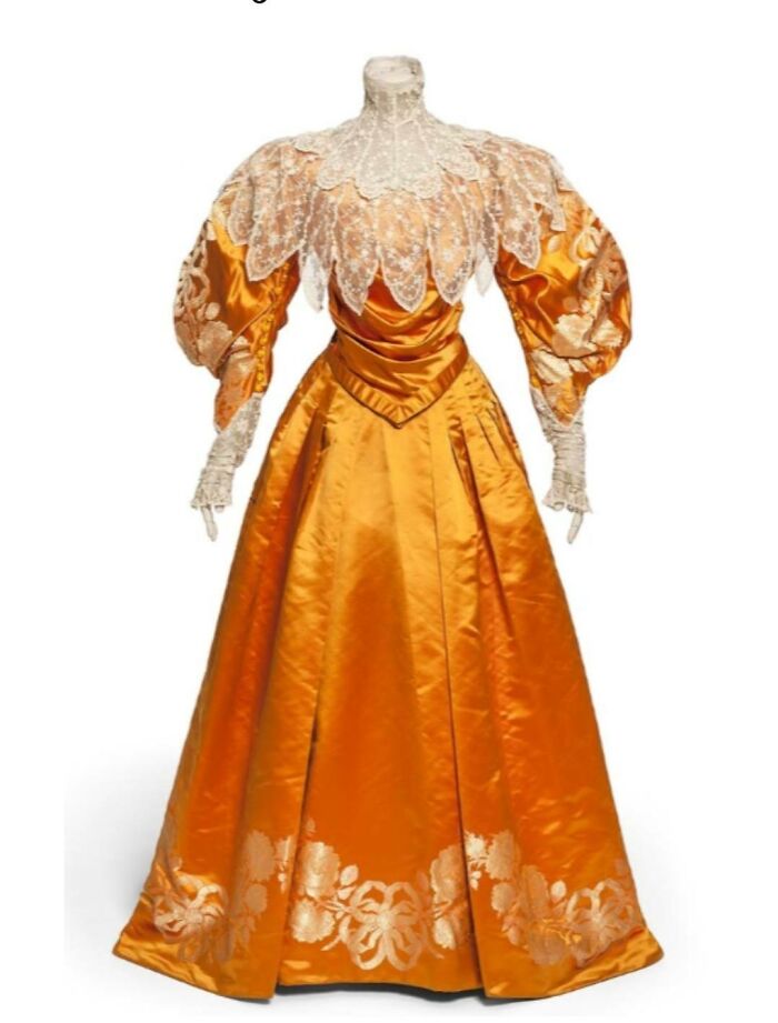 Vintage orange silk dress with lace details and puffed sleeves, showcasing culture and everyday life in the past.