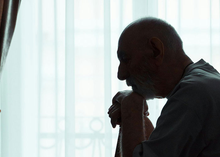 Elderly man sitting pensively by a window, illustrating unprofessional things doctors have said to patients.