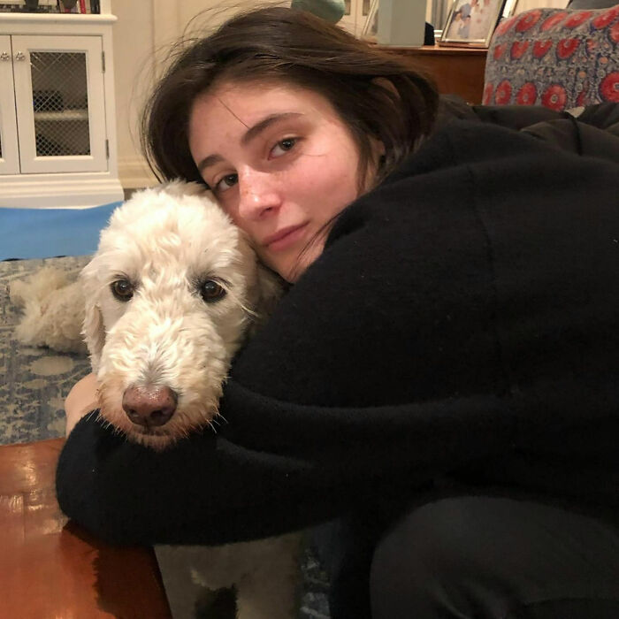 Romy Reiner hugging a white dog indoors, illustrating new details about Rob Reiner&rsquo;s daughter Romy&rsquo;s childhood fears.