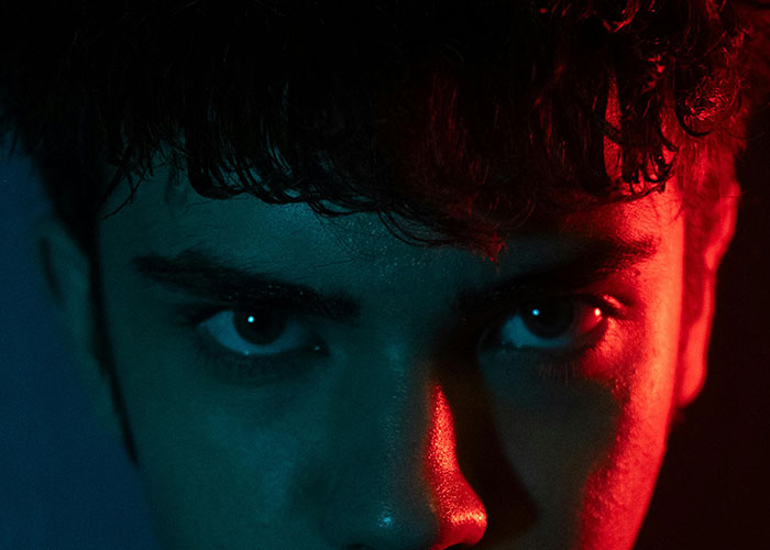 Close-up of a young man's face with dramatic red and blue lighting, reflecting intense emotions about wild ex stories.