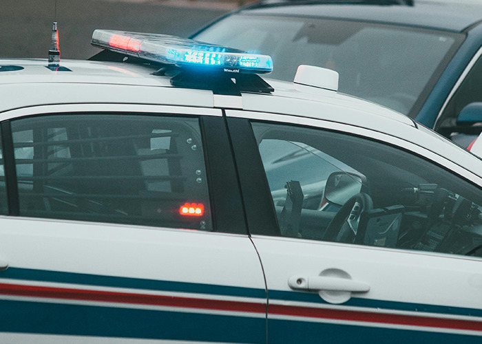 Police car with flashing lights parked near other vehicles, illustrating 911 operators handling non-emergency calls.