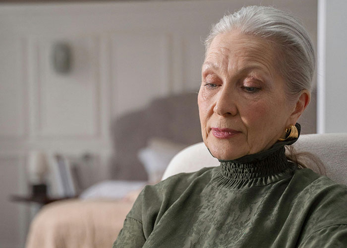Elderly woman with gray hair and gold earrings looking thoughtful, representing shocked reactions to unhinged things said by MIL.