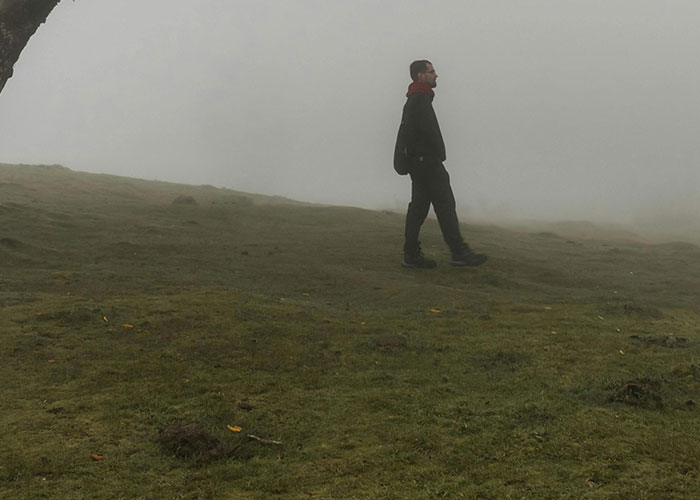 Person walking alone through foggy remote and isolated place, evoking creepy and mysterious atmosphere.