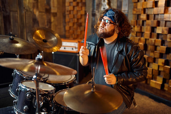 Man playing drums passionately in a music studio, representing once-famous regular job in the entertainment industry.