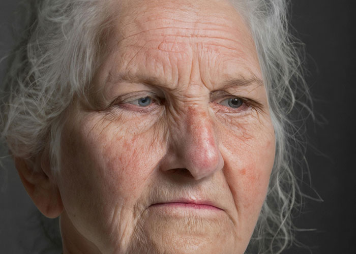 Close-up of an elderly woman with a serious expression, illustrating unhinged things a MIL might say to shock others.