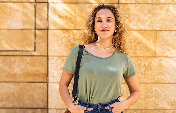 Confident young woman with curly hair wearing casual clothing, representing traits men find attractive in women.