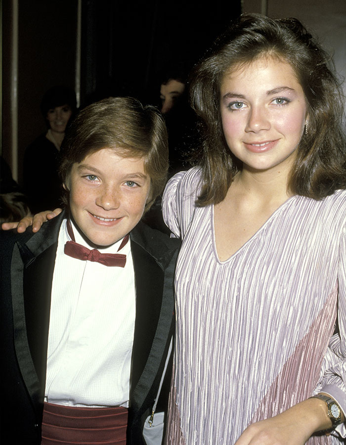 Young Jason Bateman and sister Justine smiling at a formal event, dressed in classic 1980s attire.