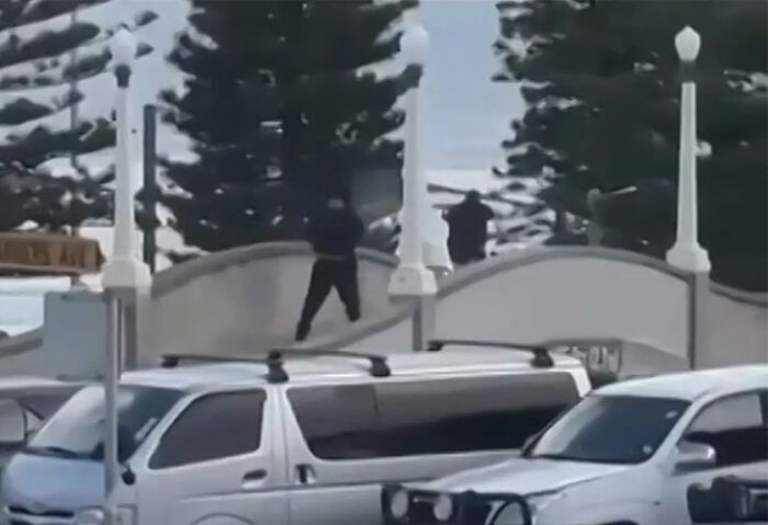 Man standing on Bondi Beach bridge near parked cars during Hanukkah event in heroic act disarming attacker. Man standing on Bondi Beach bridge near parked cars during Hanukkah event in heroic act disarming attacker.