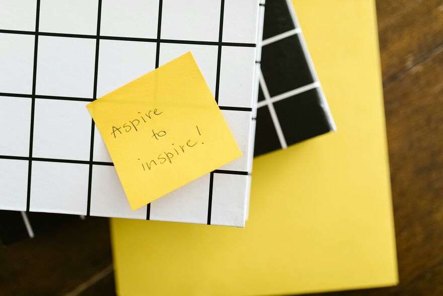 Yellow sticky note with aspire to inspire message on black and white grid notebooks symbolizing good morning message to my love ideas. Yellow sticky note with aspire to inspire message on black and white grid notebooks symbolizing good morning message to my love ideas.