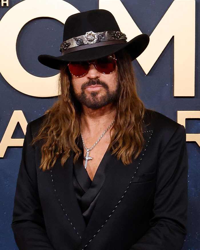 Man with long hair wearing a black hat and sunglasses at an event, related to woman claiming to be Miley Cyrus birth mother.