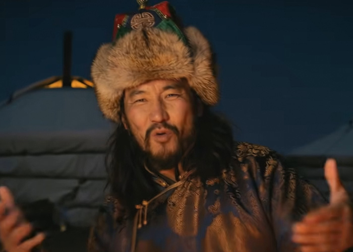 Mongolian man in traditional attire performing throat singing outdoors at night for the viral Christmas anthem of 2025.