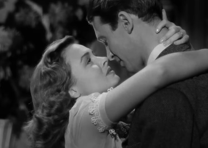 Black and white scene from a beloved Christmas classic showing a couple embracing in an emotional moment.