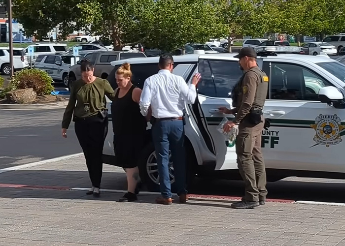 Woman being escorted by law enforcement officers near a sheriff&rsquo;s vehicle after being charged in 5-year-old daughter&rsquo;s slaying.