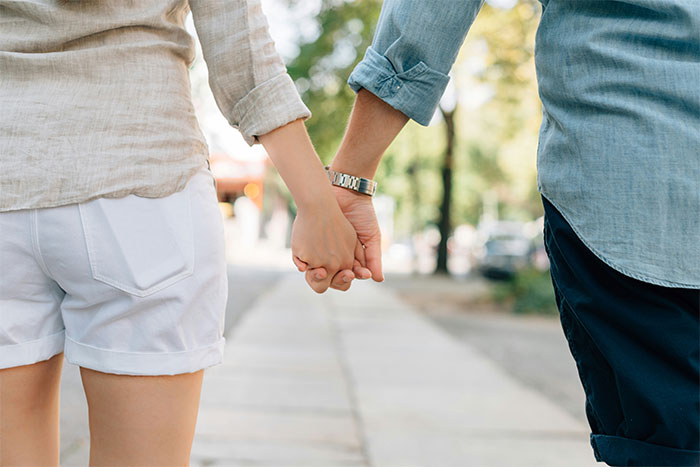 Couple holding hands while walking outdoors, capturing a quiet moment before waiter serves first date disaster unfolds. Couple holding hands while walking outdoors, capturing a quiet moment before waiter serves first date disaster unfolds.