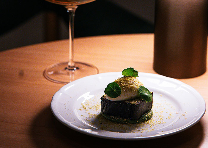 Gourmet dessert on a white plate with green garnish, highlighting luxury industry rip-offs related to rich spending.