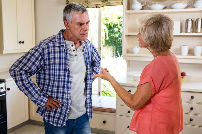 Older man and woman in kitchen having a heated family drama conversation without intending to cause conflict.