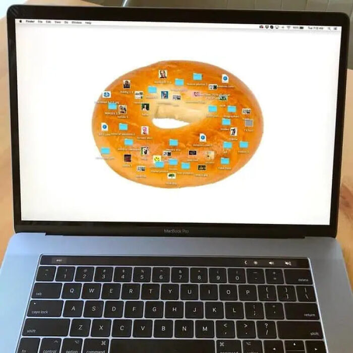 Laptop screen showing a desktop with a bagel wallpaper and icons, creating a trippy picture that seems from another reality.