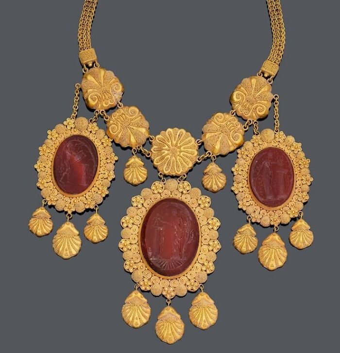Ornate vintage gold necklace with carved red gemstones, capturing culture and everyday life through old photos.