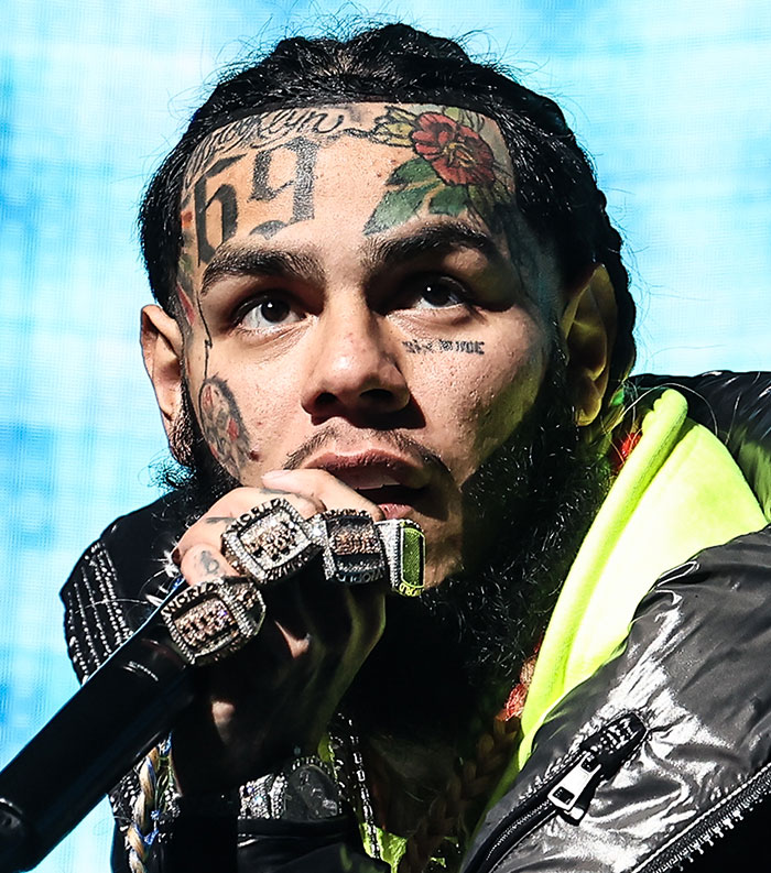 Close-up of a tattooed rapper performing on stage, representing one of the most disliked stars this year.