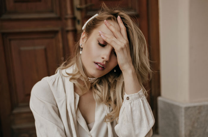 Woman covering her face with hand, looking stressed, representing husband and family call about picky eater allergies.