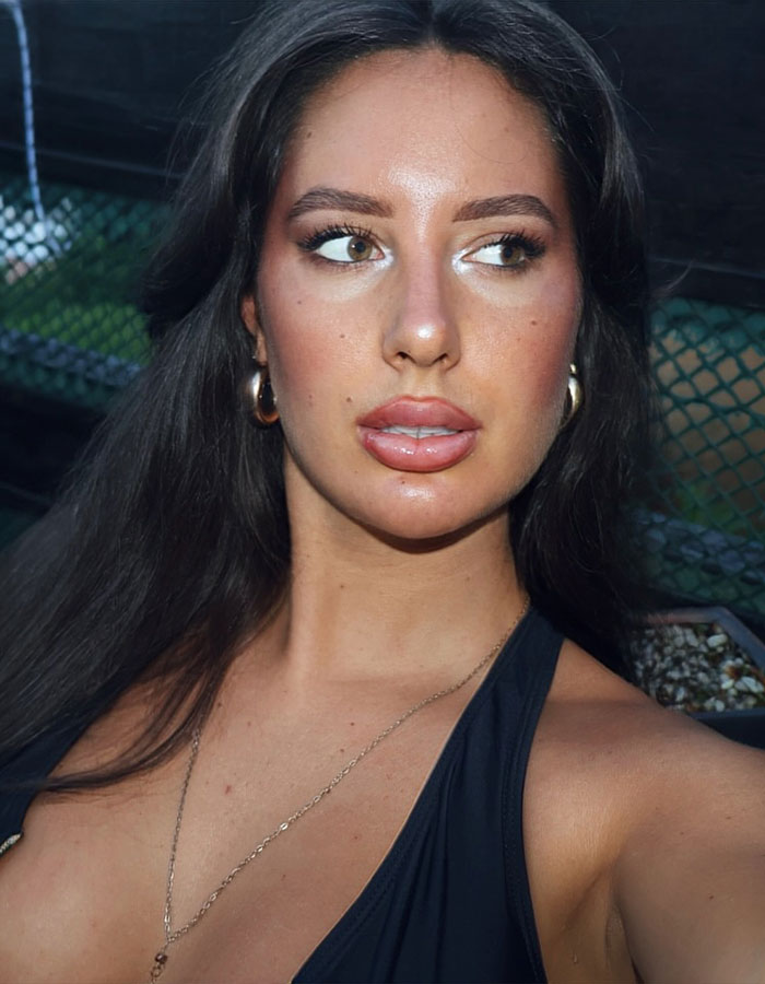 Young woman with dark hair and hoop earrings posing outdoors, first tennis star with breast enhancement now adult content creator.