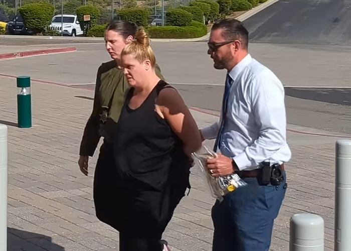 Woman being escorted by law enforcement officers outside a building related to mom's chilling Google searches case.