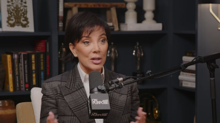 Woman speaking into a microphone in a podcast studio discussing people think celebrities closet skeletons topic.