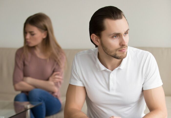 A young man and woman sit apart looking upset, illustrating unintended big family drama and conflict at home.