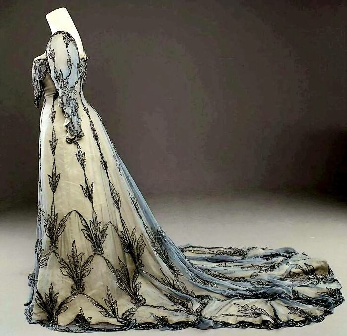 Vintage wedding dress with intricate embroidery and long train displayed on a mannequin, capturing culture and everyday life.