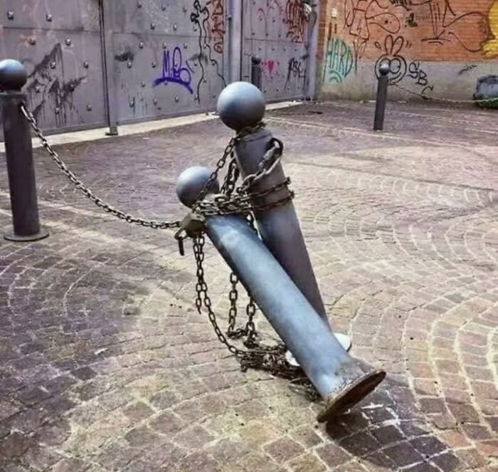 Two chained metal bollards on a cobblestone street create a trippy picture that seems plucked from another reality.