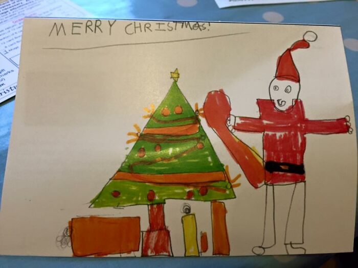 Child's drawing of Santa next to a Christmas tree and presents, showcasing funny drawings by kids with no filter.