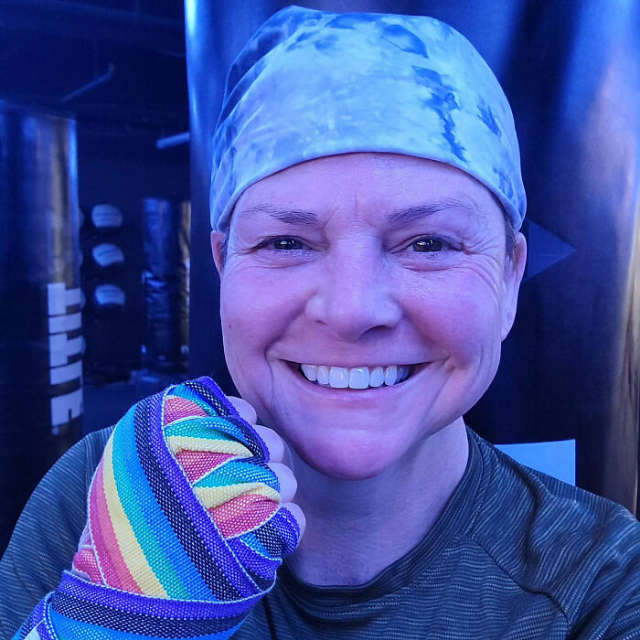 Smiling woman wearing a headscarf and rainbow hand wrap at a boxing gym, related to Marvelous Mrs. Maisel actress news.