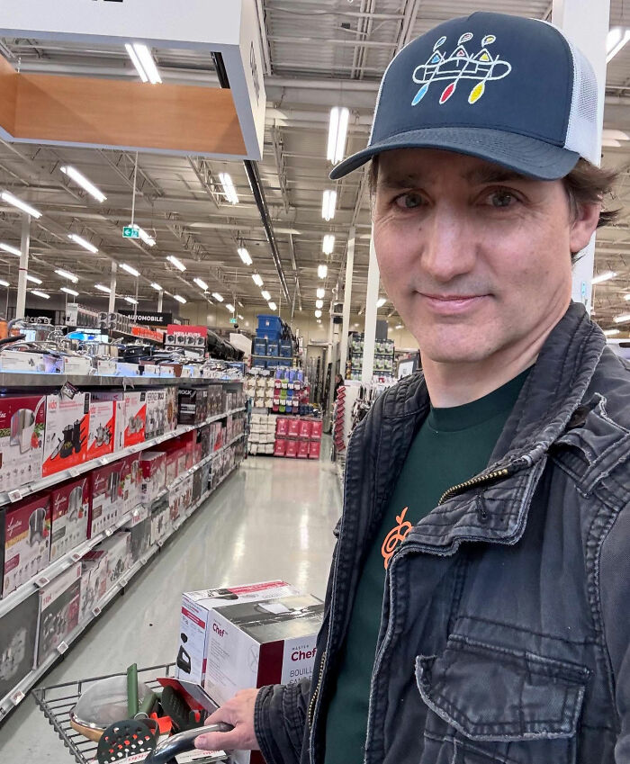 Justin Trudeau shopping in a store aisle, casually dressed with a cap, holding a cart with kitchen appliances. Justin Trudeau shopping in a store aisle, casually dressed with a cap, holding a cart with kitchen appliances.