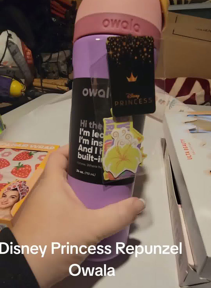 Hand holding a purple Disney Princess Repunzel Owala water bottle in a Christmas gift haul for daughter. Hand holding a purple Disney Princess Repunzel Owala water bottle in a Christmas gift haul for daughter.