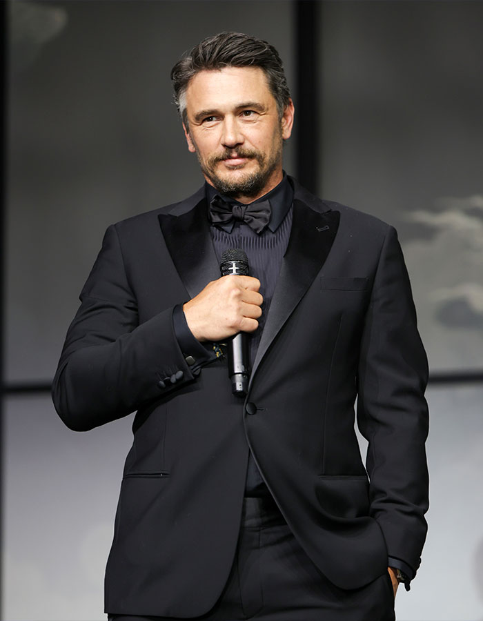 James Franco in a black tuxedo holding a microphone, speaking at an event, reflecting on being cast out of Hollywood. James Franco in a black tuxedo holding a microphone, speaking at an event, reflecting on being cast out of Hollywood.
