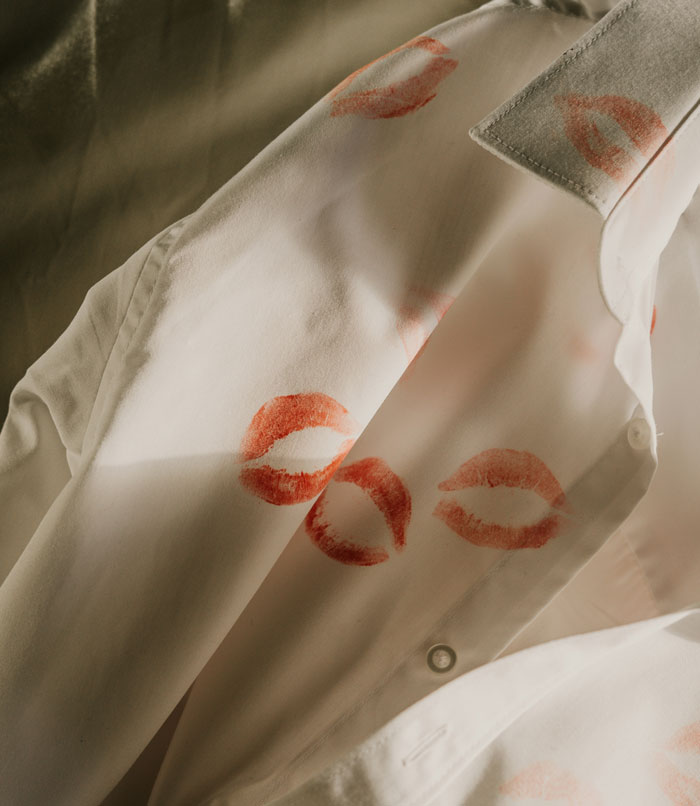 White shirt with several red lipstick kiss marks, symbolizing forgiveness challenges faced by couples in relationships.